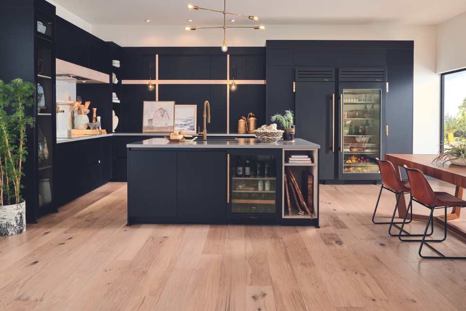 white oak engineered hardwood in navy blue kitchen with gold hardware and wood dining table